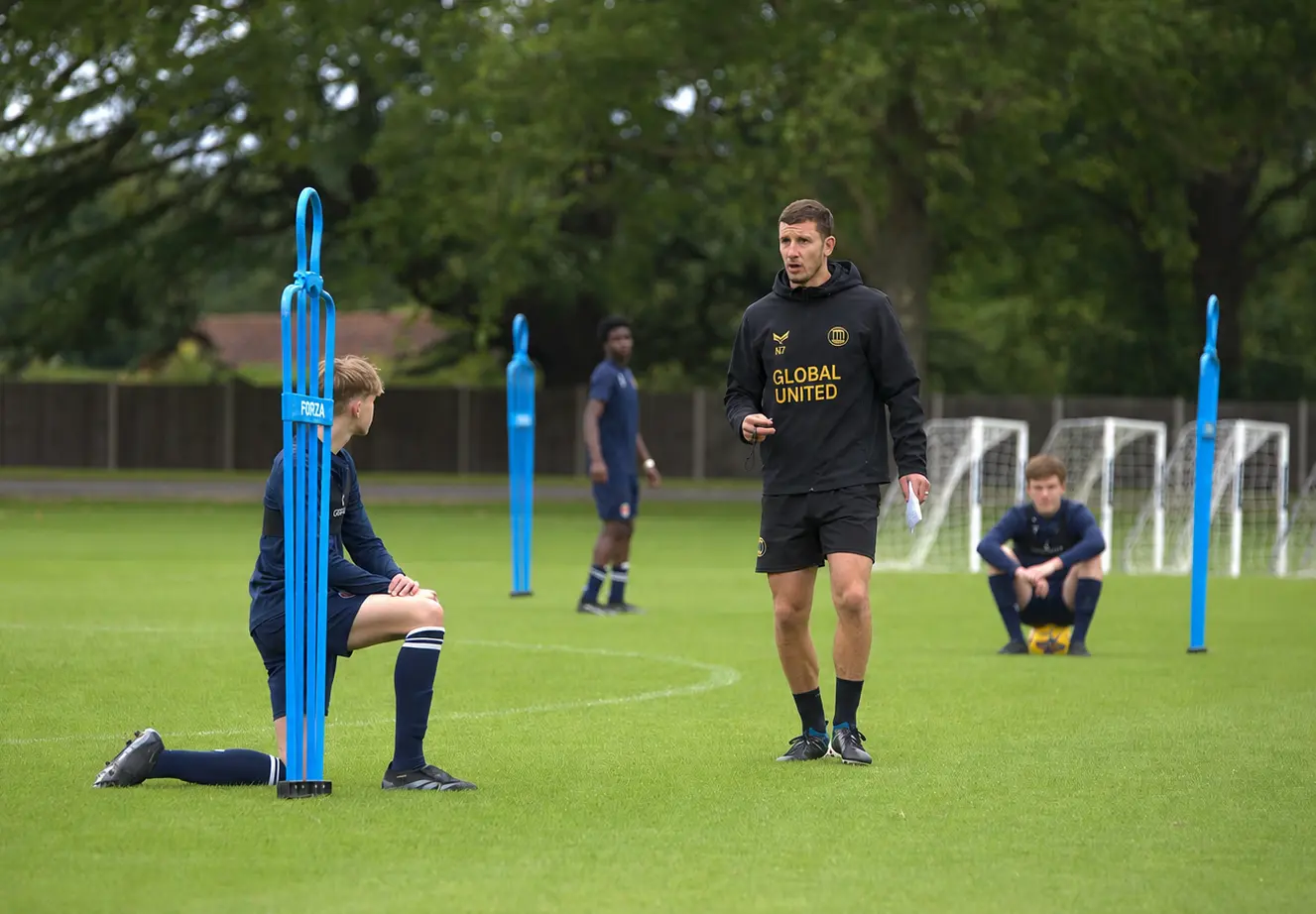 A Global United coach leading an on-pitch session